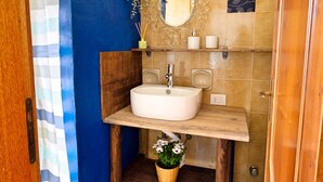 A bathroom with a wooden vanity, a white sink, a mirror, and a shower area. - Blueindaco Sellia Marina - Room Apartment Calabria (Sellia Marina)