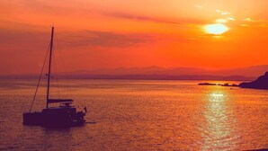 A sunset over a calm sea with a sailboat. - Blueindaco Sellia Marina - Room Apartment Calabria (Sellia Marina)