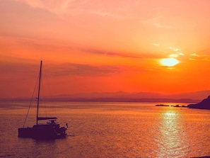 Ein Sonnenuntergang über einem ruhigen Meer mit einem Segelboot.