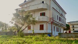 A multi-story building with balconies, a tree in front, and a clear sky. - Blueindaco Sellia Marina - Room Apartment Calabria (Sellia Marina)