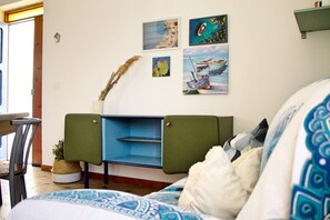 A room with a bed, a green cabinet, a wall with artwork, and a window.