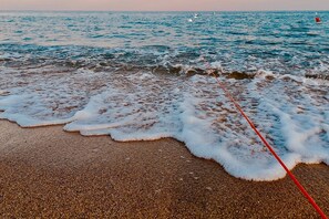 A beach with waves and a red line on the sand.