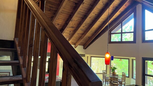A spacious living area with a wooden staircase, large windows, and a dining area with a table and chairs. - Cabaña El Roble Mazamitla (Mazamitla)