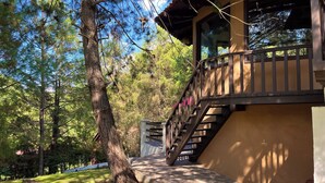 A wooden staircase leading to a balcony with a view of a forested area. - Cabaña El Roble Mazamitla (Mazamitla)