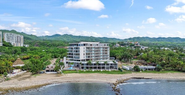 Un hotel moderno con varios pisos, piscina y vista a la playa.