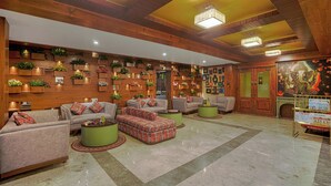 Un vestíbulo amplio con varias zonas de estar, paneles de madera y plantas decorativas.