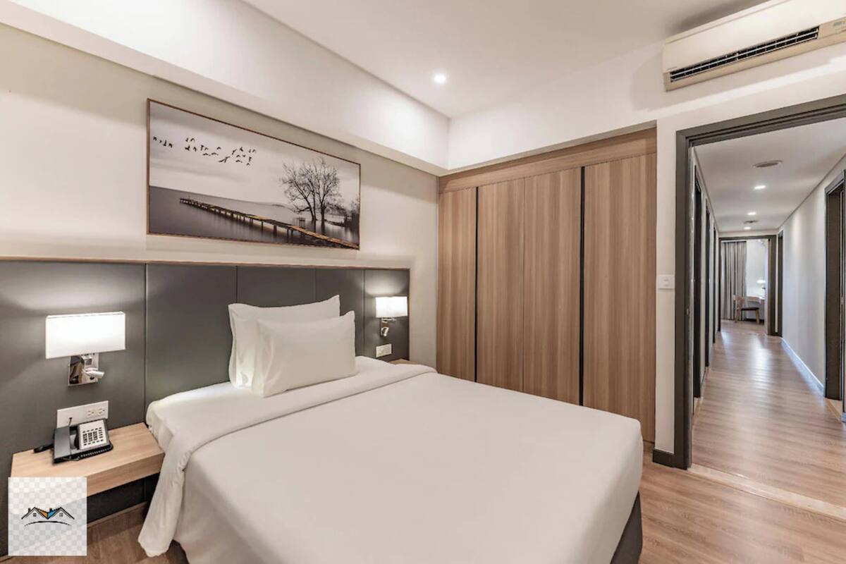 Una camera d'albergo con un letto, abat-jour, telefono, un quadro appeso al muro e un armadio in legno.
