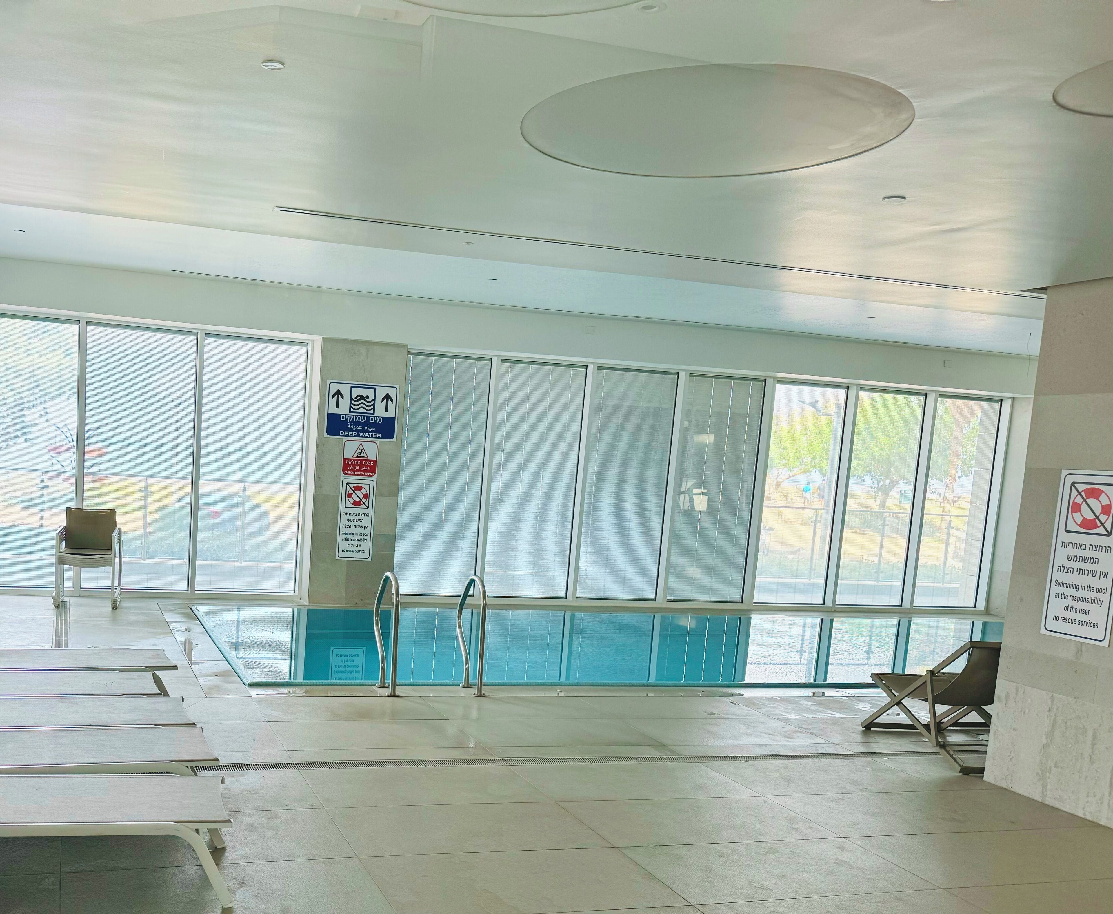 A swimming pool area with clear signage, including a 'Deep Water' sign, and a 'No Swimming in the Pool at Your Own Risk' sign.