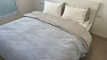 Una cama bien hecha con una colcha de estampado geométrico y dos almohadas.