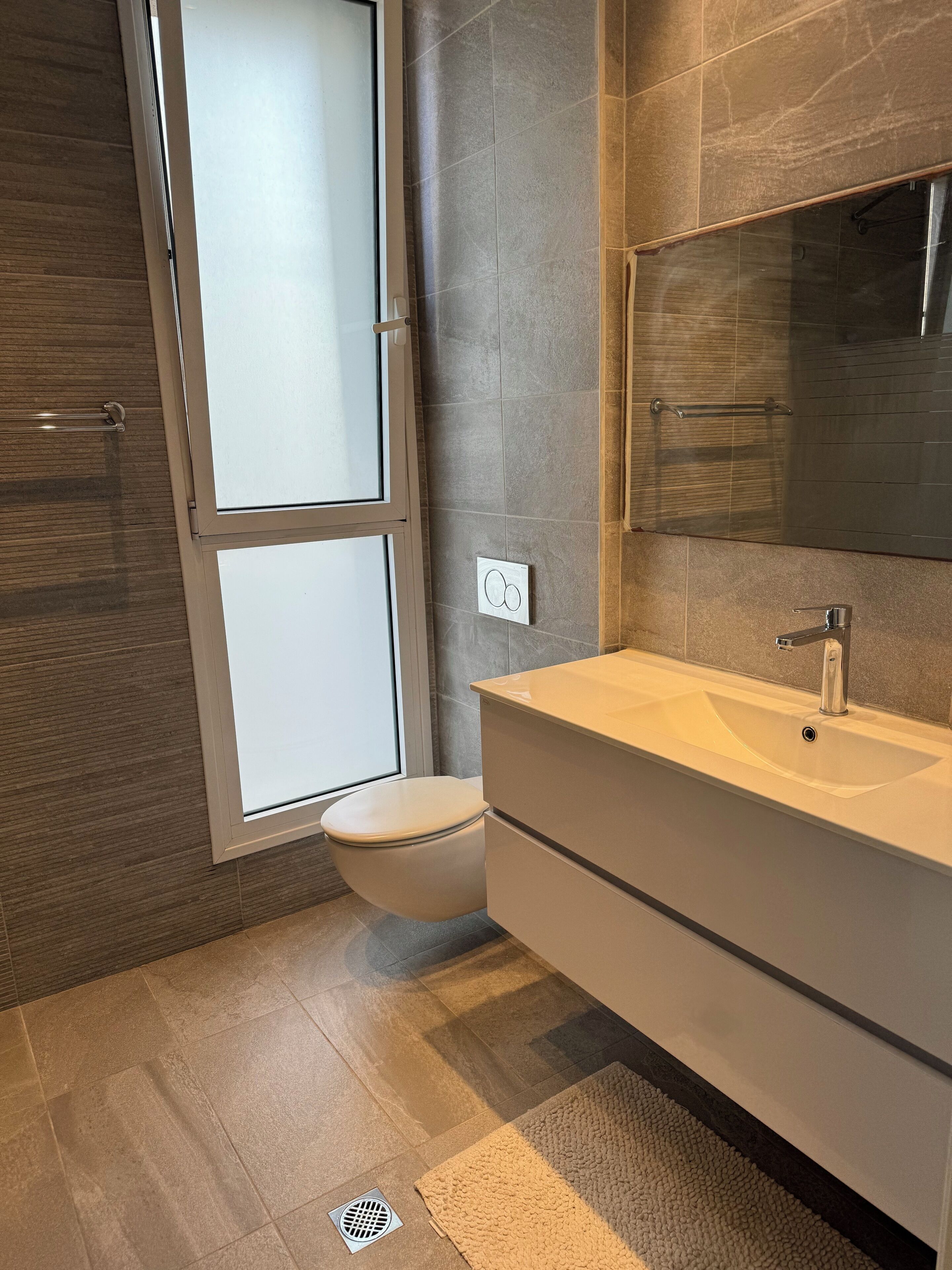 A modern bathroom with a toilet, a sink, and a shower area.