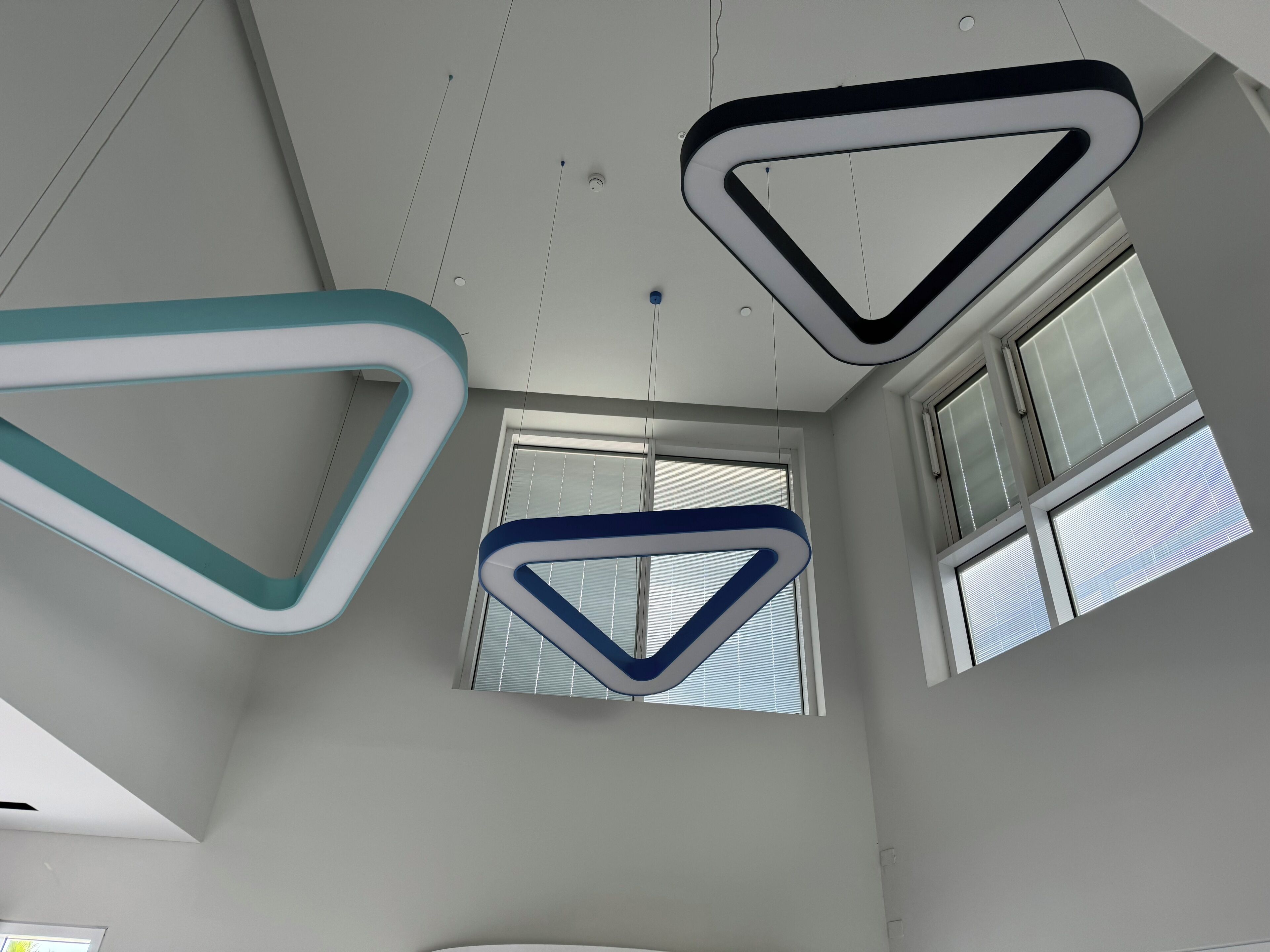 Een modern interieur met geometrische lampen en grote ramen.