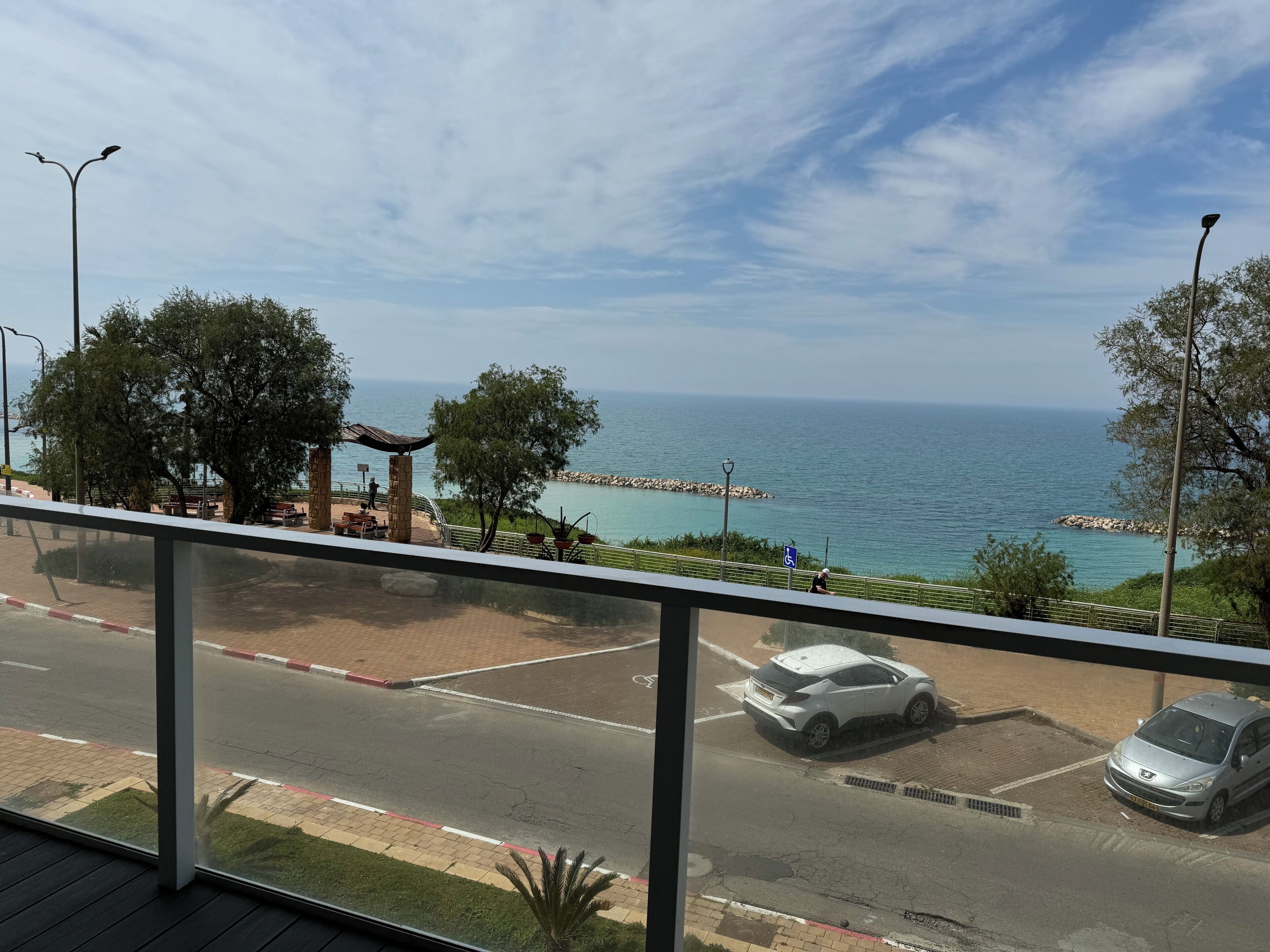 Une vue sur la côte avec une promenade dallée, des bancs et un espace de stationnement.