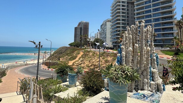 Une zone urbaine côtière dotée d’une plage, d’une route sinueuse et de bâtiments modernes.