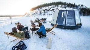 Un grupo de personas sentadas en sillas en un entorno nevado al aire libre, con una estructura tipo tienda de campaña al fondo.