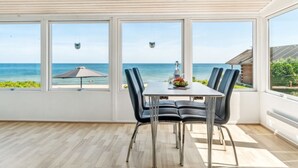Ein Essbereich mit Tisch und Stühlen, großen Fenstern mit Meerblick und einem Deckenventilator.