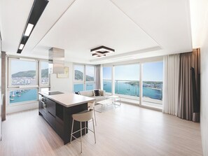Una cucina moderna con un'isola grande, una zona pranzo con divano e ampie finestre vista mare.