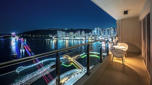 A balcony with a city view, railing, and a table with chairs.