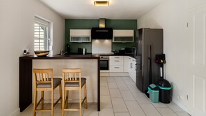 Eine moderne Küche mit Kochinsel, weißen Schränken, einer schwarzen Mikrowelle und einem Edelstahl-Kühlschrank.