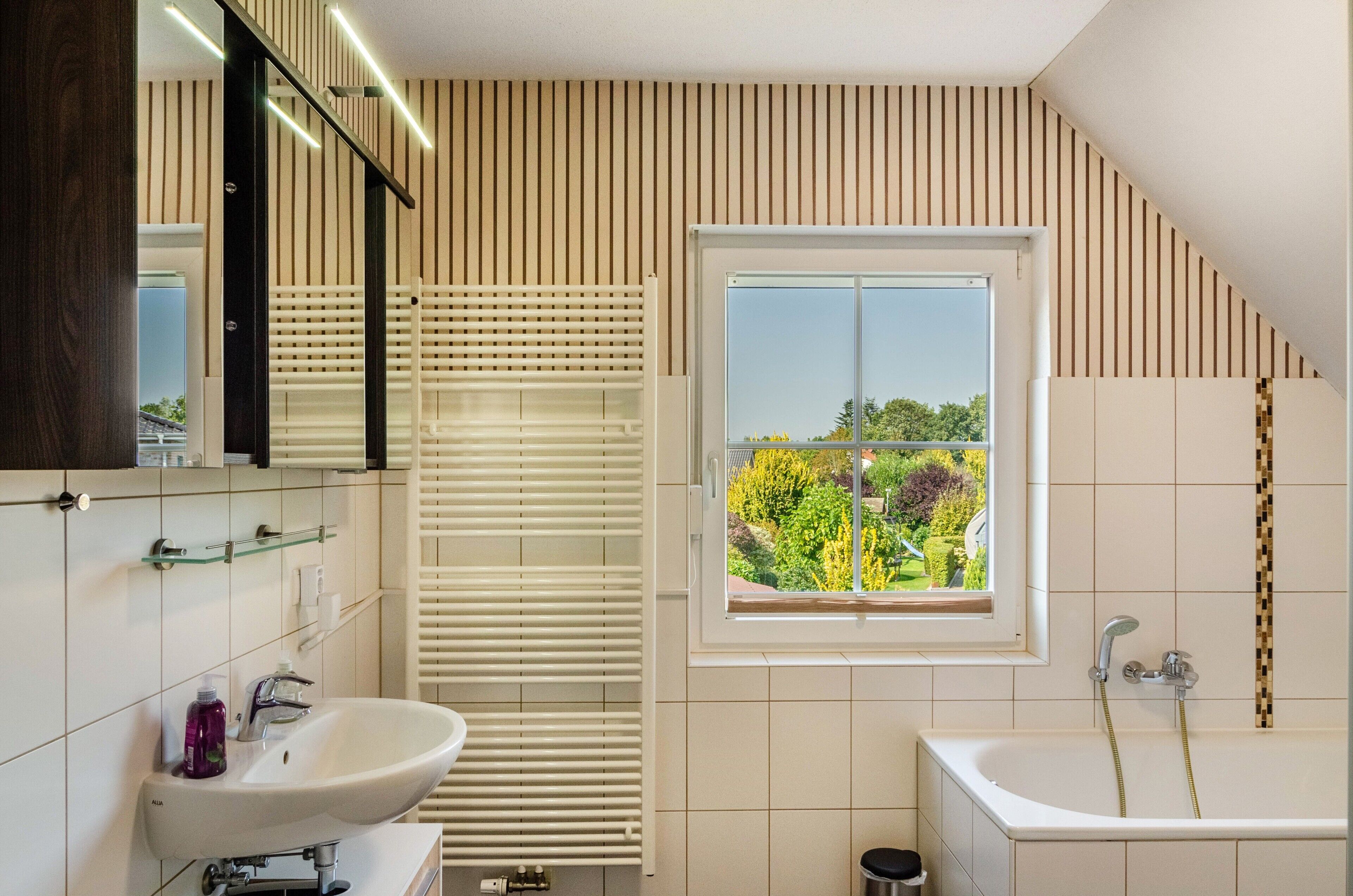 Un baño moderno con un ventanal amplio, una bañera y una zona de ducha.