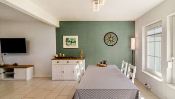 Una habitación con cama, escritorio, televisor, reloj y ventana.