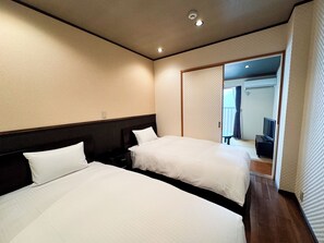 A hotel room with two beds, a TV, and a sliding door leading to a balcony.