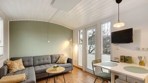 Un salon comprenant un canapé, une table à manger et un téléviseur fixé au mur.