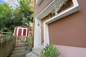 A building with a red and white striped structure in the background, a wooden gate, and steps leading to a door with a window above.