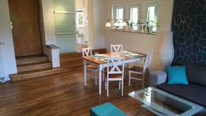Una sala de estar moderna con un sofá, una mesa de centro de vidrio y una zona de comedor con una mesa y sillas.