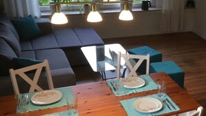 Un comedor con una mesa de madera dispuesta para cuatro personas, rodeada de sillas blancas con respaldo de cruce.