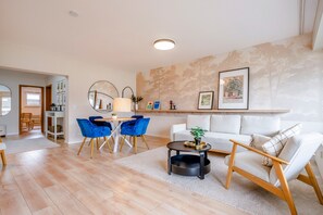 A modern living room with a white sofa, blue chairs, a round coffee table, and a fireplace.