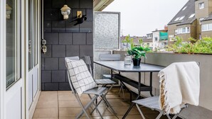 Un balcón con una mesa, sillas, una planta en maceta y una lámpara colgante.