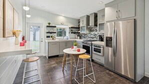 A modern kitchen with stainless steel appliances, a central island, and a view to the outside. - Welcome to Space Coast Retreat (Cocoa Beach)