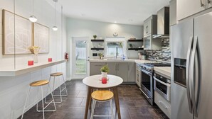 A modern kitchen with a central island, stainless steel appliances, and a view to the outdoors. - Welcome to Space Coast Retreat (Cocoa Beach)
