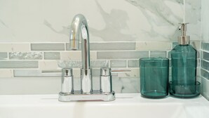 Un lavabo de salle de bain avec un robinet chromé, un distributeur de savon et deux récipients en verre.