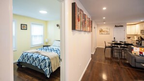 A bedroom with a bed, a dining area with a table and chairs, and a kitchen area with cabinets and a microwave.