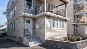A multi-story residential building with a front entrance, a small porch, and a visible balcony on the second floor.