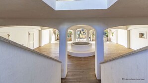 A modern interior with a central circular seating area, white walls, and wooden flooring. - Gardenia Luxury (Palau)