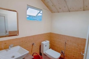 Un baño pequeño con techo de madera, una ventana, un lavamanos y un inodoro.