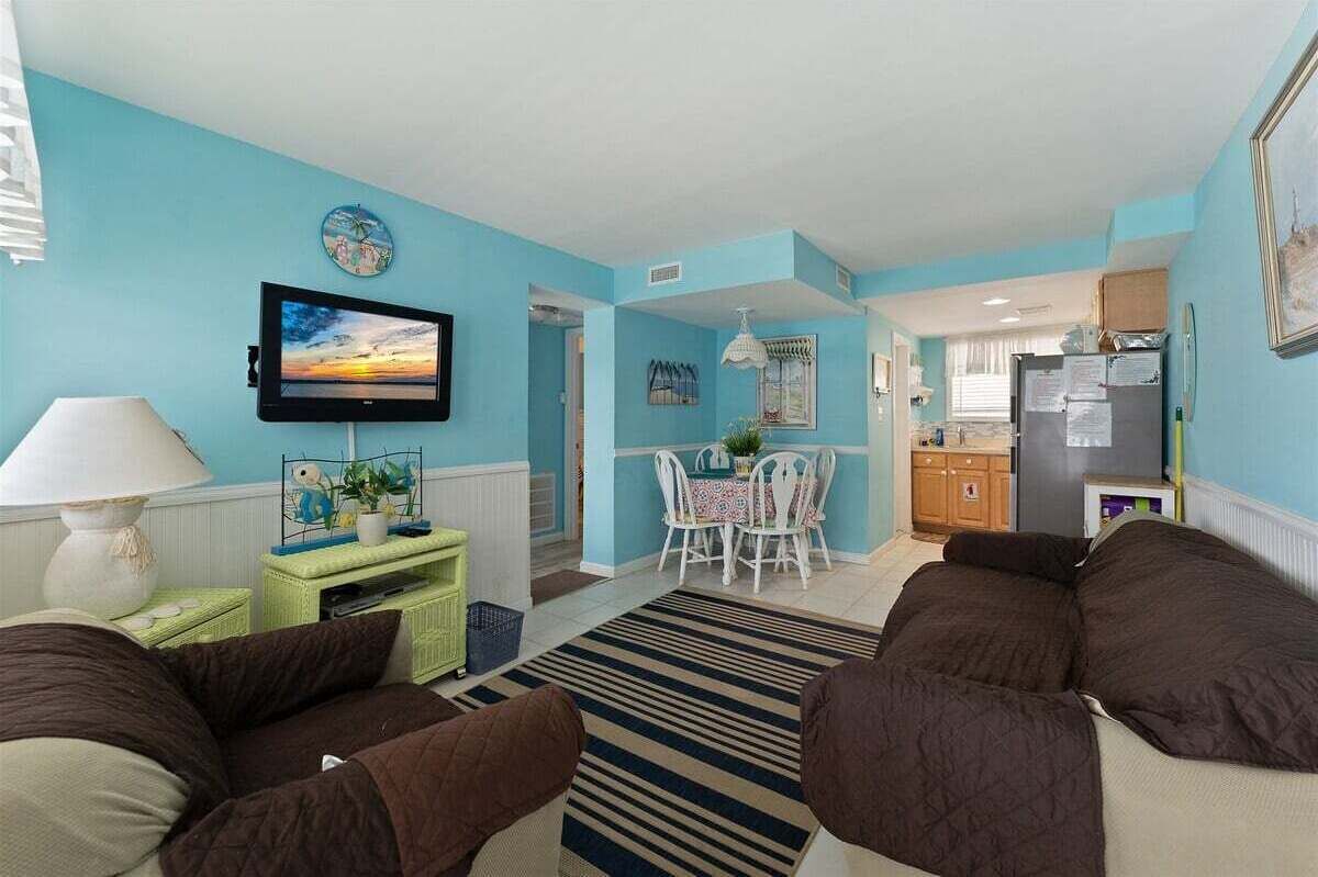 A living room with a TV, sofa, dining table, and kitchen area.