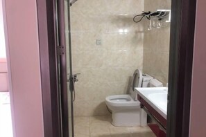 A bathroom with a toilet, sink, and glass shower enclosure. - Golden Bay 38 Homestay (Cangnan)