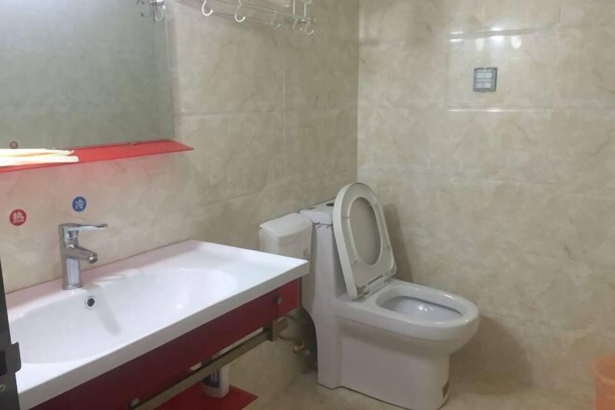 A bathroom with a white sink, red cabinet, and a toilet.