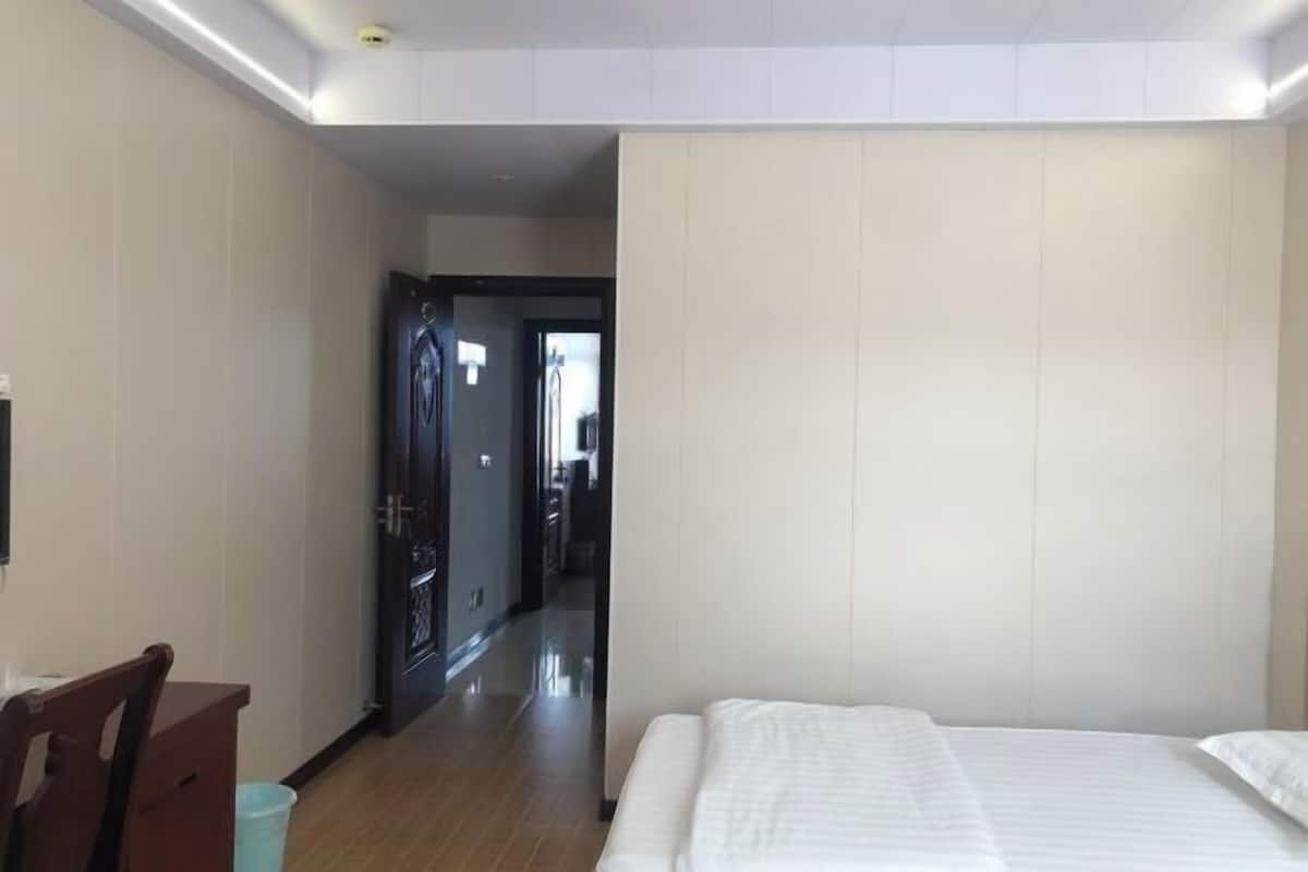 A hotel room with a bed, a desk, and a chair.