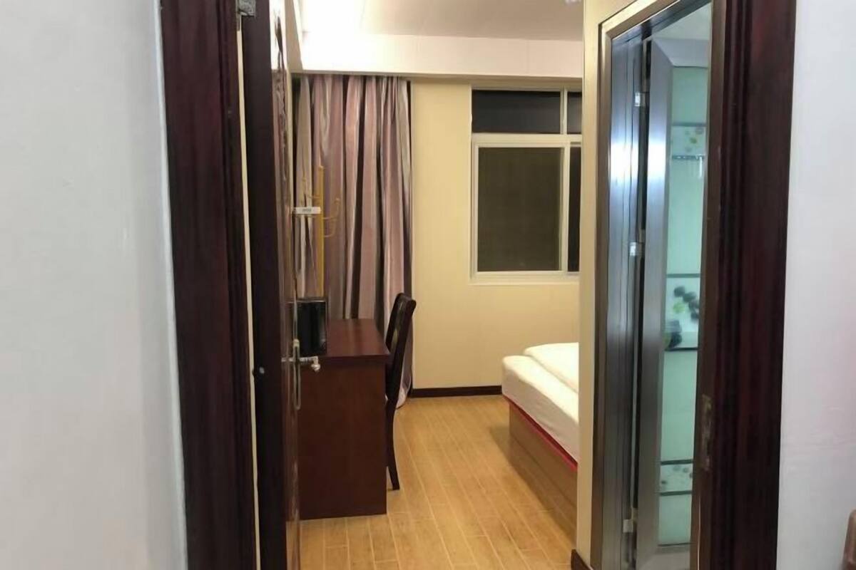A room with a bed, a desk, a chair, a window, and a door.
