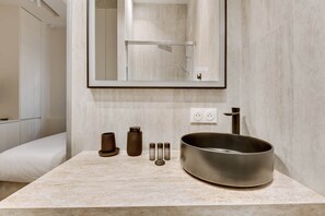 Une salle de bain avec un grand lavabo rond, un miroir et une douche.