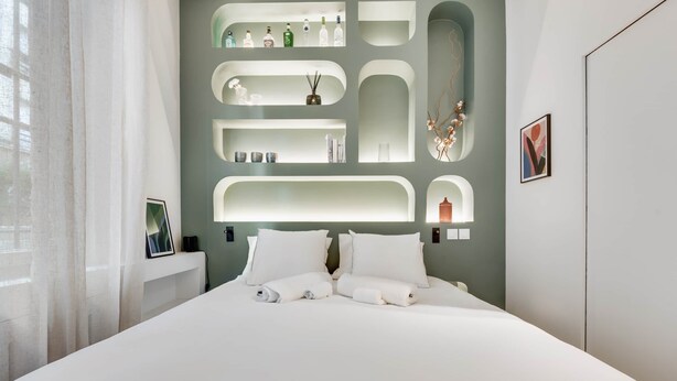 A modern bedroom with a large bed, built-in shelving, and a framed picture on the wall. - Luxueux Studio Cosy à Bastille (Paris)