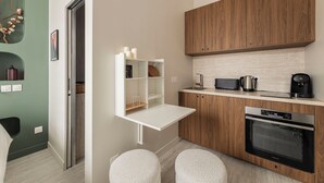 A modern kitchen with wooden cabinets, a built-in oven, and a white countertop. - Luxueux Studio Cosy à Bastille (Paris)