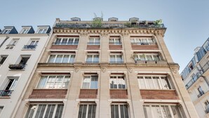 A multi-story building with a classical architectural style, featuring a central entrance with a large doorway and a symmetrical facade with evenly spaced windows and balconies. - Luxueux Studio Cosy à Bastille (Paris)