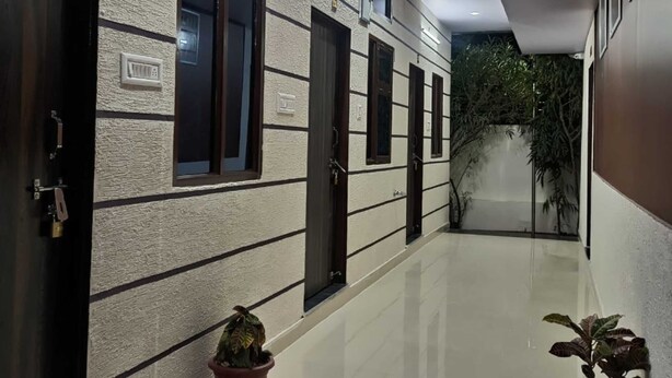 A hallway with doors, potted plants, and a tiled floor. - Maheshwari Homestay By GRB (Jamwa Ramgarh)