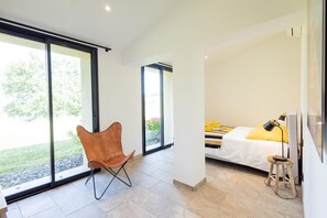 Enjoy a serene view of the garden from the comfort of your room, featuring a large sliding glass door and a stylish seating area.