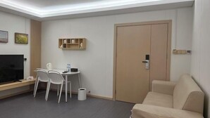 A hotel room with a TV, a desk with chairs, a sofa, and a door. - Changsha Antman Good Living (Provincial Children's Hospital Yali Middle School) (Changsha)